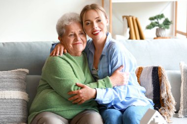 Genç bir kadın ve büyükannesi evde sarılıyorlar.