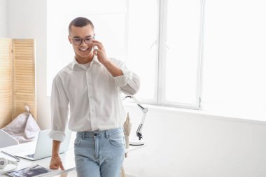 İş yerinde cep telefonuyla konuşan yakışıklı genç işadamı.