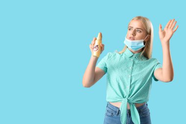 Tıbbi maskeli genç bir kadın ve mavi arka planda sivrisinek kovucu.