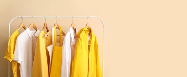 Bej duvarda asılı şık kıyafetler ve çantalar. Tasarım için pankart