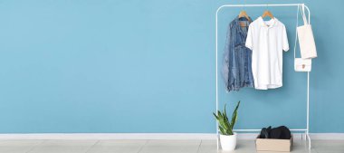 Şık kıyafetler, aksesuarlar ve mavi duvarın yanındaki bitki örtüleriyle doldur. Tasarım için pankart