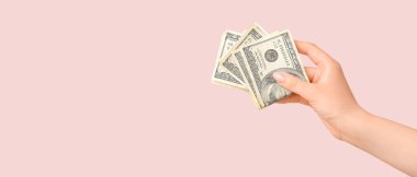 Pembe zemin üzerinde dolar banknotları tutan kadın metin için yer var.