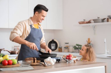 Babası mutfakta yemek yaparken tatlı küçük bir kız.