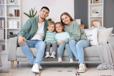 Aileleri evdeki kanepede oturan küçük çocuklar.