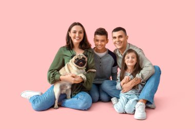Aileleri ve köpekleri pembe arka planda oturan küçük çocuklar.