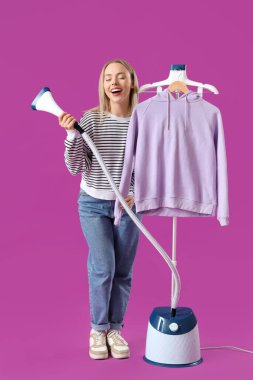 Modern buharlı güzel bir kadın ve mor arka planda giysileri var.