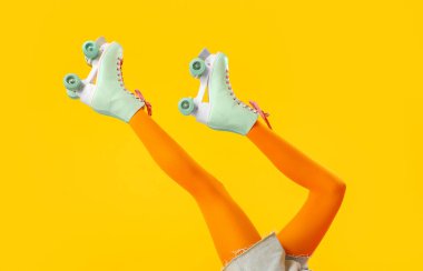 Sarı arka planda patenli kadın bacakları