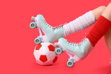 Kırmızı arka planda topu olan patenli bir kadın.