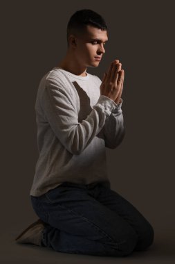 Genç adam koyu arka plan üzerinde dua