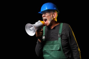 Olgun madenci siyah arka planda megafona bağırıyor.