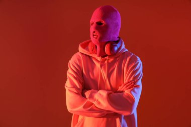 Kırmızı arka planda kulaklıkları olan kar maskeli yakışıklı bir genç.