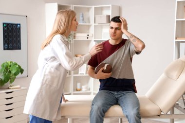 Kadın doktor klinikte beyin sarsıntısı geçiren rugby oyuncusunu inceliyor.