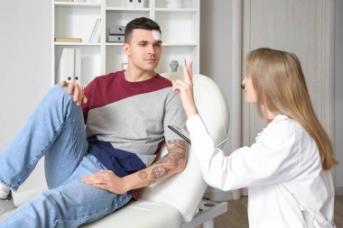 Kadın doktor klinikte beyin sarsıntısı geçiren adamı muayene ediyor.