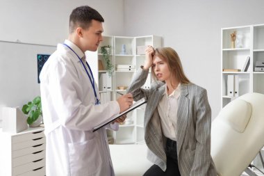 Beyin sarsıntısı geçiren genç bir iş kadını klinikteki doktoru ziyaret ediyor.