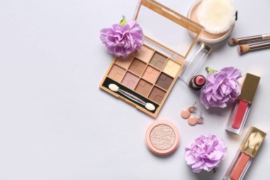 Küpeli dekoratif kozmetik ürünler ve beyaz arka planda çiçekler