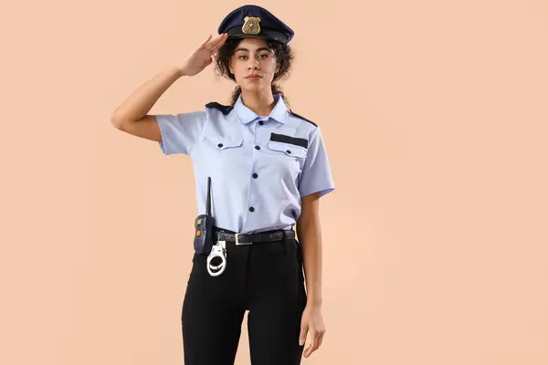 African-American female police officer saluting on brown background