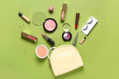 Makyaj ürünleri ve yeşil arkaplanda konfeti bulunan kozmetik çanta.