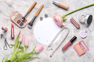 Çiçekli boş kart, makyaj ürünleri ve hafif grunge arka planda aksesuarlar