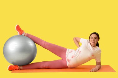 Güzel, genç, hamile bir kadın yoga minderinde antrenman yapıyor.