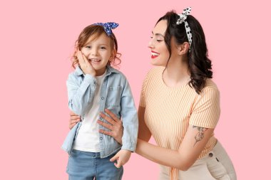 Pembe arka planda güzel bir kadın ve kızı.