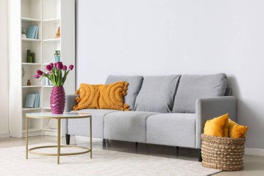 Masanın üzerinde güzel mor laleler olan modern oturma odası ve vazo.