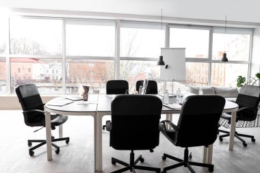 Masa, koltuklar, dizüstü bilgisayar ve kırtasiye şık bir konferans salonunda iş görüşmesi için hazırlanıyor.