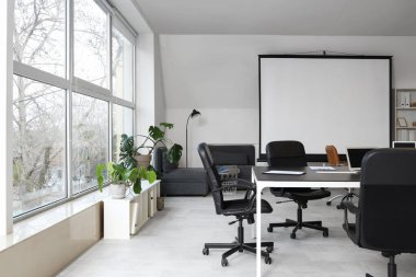 Masası, ekranı ve koltukları olan şık bir konferans salonu.