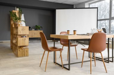 Masası, ekranı ve koltukları olan modern bir konferans salonu.