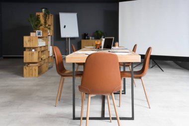 Masası, ekranı ve koltukları olan modern bir konferans salonu.