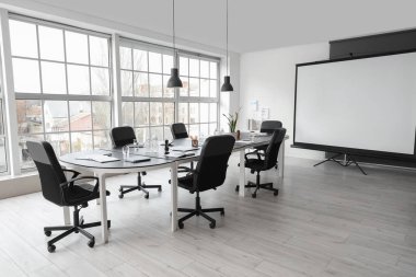 Masa ve projektör ekranlı ofis içi toplantı için hazırlandı