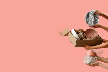 Pembe arka planda taşınma kutusu ve mutfak sofra takımı olan kadınlar