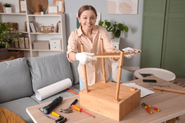 Evinde ahşap masa toplayan güzel, genç bir kadın.