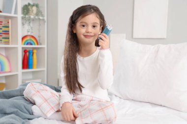 Yatak odasında astım spreyi olan küçük kız.