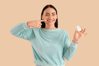 Güzel, genç, mutlu bir kadın bej arka plandaki diş ipini işaret ediyor.