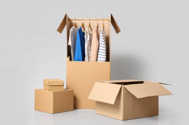 Gri arka planda giysileri olan gardırop kutuları.