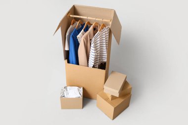 Gri arka planda giysileri olan gardırop kutuları.