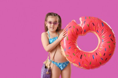 Mor arka planda donut şeklinde şişirilebilir halkası olan şirin küçük kız.