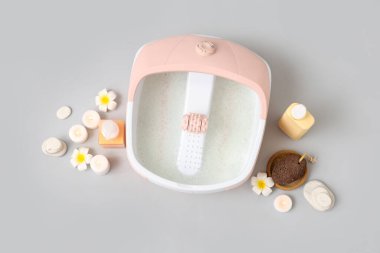 Ayak banyosu, kozmetik ürünleri, sünger taşları ve gri arka planda kaplıca taşları