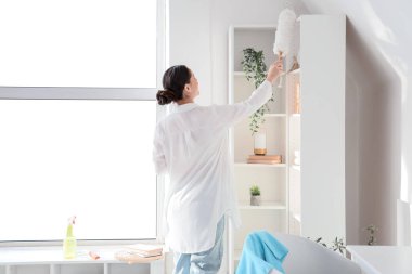 Genç hamile bir kadın. Evinde toz bezi ile temizlik yapıyor.