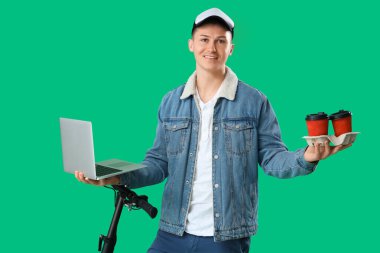 Yeşil arka planda kahve, laptop ve scooter kullanan erkek kurye.