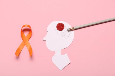 Pembe arka planda turuncu kurdele, kalem ve kağıt insan kafası. Çoklu Skleroz Farkındalık Ayı