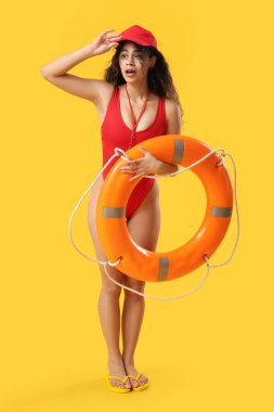 Sarı arka planda halka şamandırası olan Afro-Amerikan kadın cankurtaran.