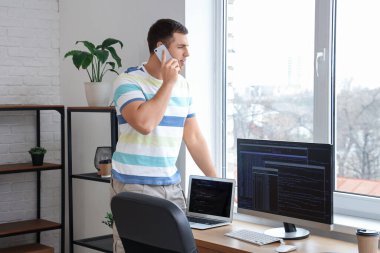 Ofisinin yakınında telefonla konuşan erkek programcının portresi.