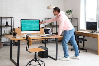 Modern ofiste laptop ve bilgisayarla çalışan erkek programcının portresi
