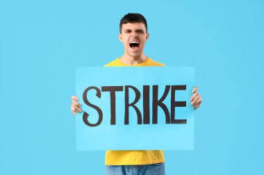 Mavi arka planda kelime STRIKE ile pankart tutan genç adam protesto