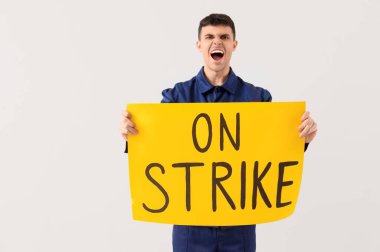 Işık arkaplanına karşı üzerinde ON STRIKE metni olan mekanik pankart protesto ediliyor