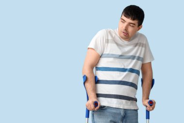 Mavi arka planda koltuk değnekleri olan genç bir adam. Ulusal Beyin Felci Farkındalığı Ayı