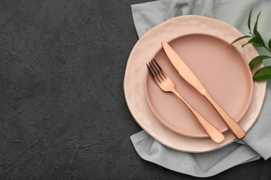 Siyah arkaplanda pembe tabaklar ve çatal bıçak takımı