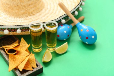 Sombrero, marakas, limon, nachos ve yeşil arka planda tekila.