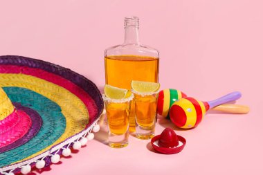 Sarı arka planda bir şişe tekila, shot, limon ve marakas.